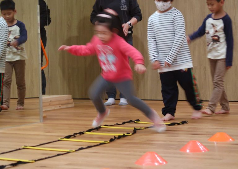 兒童快速通過地板上的繩梯 (Agility Ladder),訓練腳步變換速度與敏捷度 (Agility),有效提升神經系統對肌肉的控制與下肢爆發力。