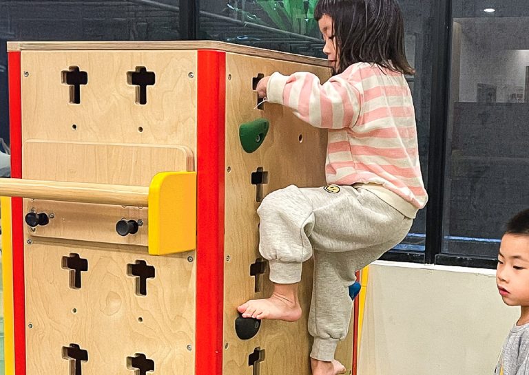 幼兒專注攀爬木製攀岩箱,訓練手腳並用的交叉協調 (Cross-lateral Coordination) 能力與垂直空間感,強化背部與四肢肌肉發展。