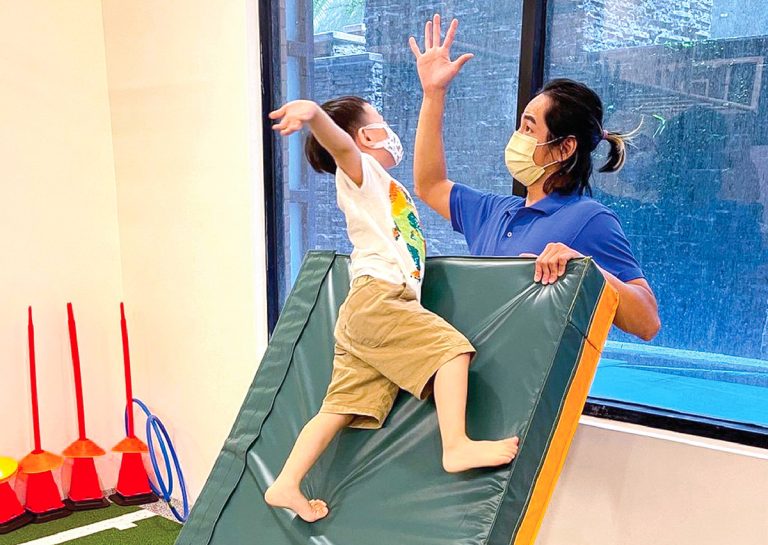 幼兒成功攀爬斜坡軟墊後與教練擊掌 (High Five),透過正向強化 (Positive Reinforcement) 建立孩子的運動自信與成就感,鼓勵主動挑戰自我。