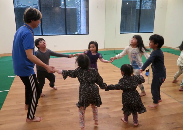 孩子們手牽手圍成圓圈進行團體律動,透過音樂與肢體接觸培養節奏感 (Rhythm) 與群體歸屬感,是兒童社交情感學習 (SEL) 的重要環節。