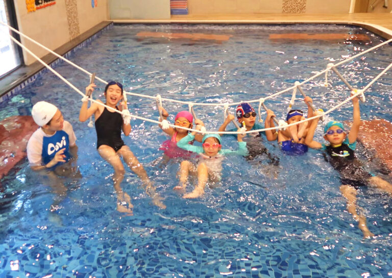 兒童挑戰水上繩索攀爬架,這項結合體適能 (Physical Fitness) 的游泳課程能強化孩子的上肢握力與核心肌群,並培養面對挑戰的冒險精神。