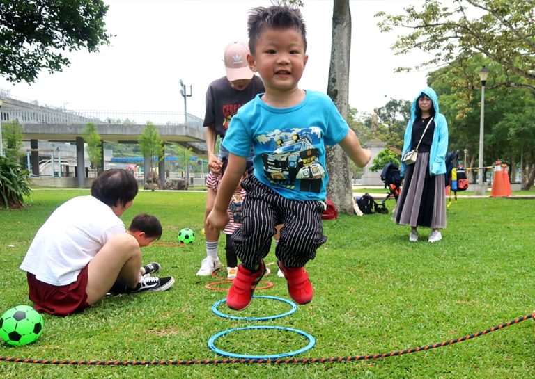男童在戶外公園進行連續跳圈圈練習,訓練雙腳起跳的協調性與下肢爆發力,並在自然環境中提升對距離感的視覺判斷。