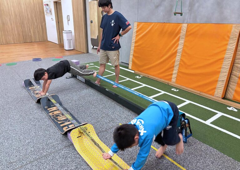 兒童在 Oovi 教練指導下利用彎板 (Slackboard) 進行支撐練習,這項動作能強化核心肌群 (Core Muscles) 與肩帶穩定度,是提升孩子坐姿端正與專注力的基礎訓練。
