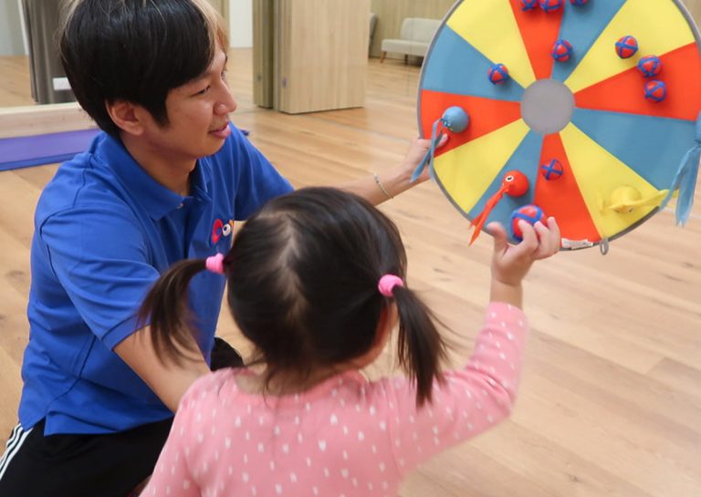 教練引導幼兒使用黏黏球進行標靶投擲,這項精細的目標導向遊戲能訓練孩子長時間的視覺專注力與手部肌肉控制的精準度。