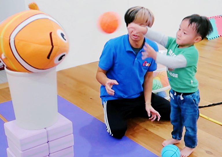 幼兒練習將球投向尼莫玩偶目標,透過遊戲化教學引導孩子學習正確的上肢投擲姿勢,為未來學習複雜球類運動打下良好的協調基礎。