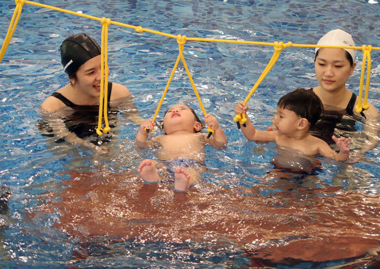 家長輔助幼兒抓握水上懸吊繩索,進行仰漂 (Back Float) 與核心平衡訓練,增進孩子在水中的前庭覺發展與穩定度。