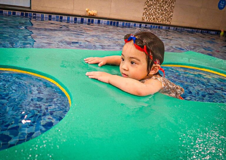 幼兒練習攀附於大型浮毯邊緣,模擬岸邊攀爬 (Wall Climbing) 自救技巧,訓練手臂肌肉力量與水中生存能力 (Survival Skills)。