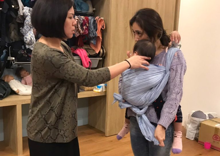 Oovi 專業顧問一對一協助媽媽調整長布揹巾 (Woven Wrap) 的布料張力,確保寶寶脊椎呈現健康的 C型背,並透過分段拉緊技巧解決產後媽媽腰痠背痛的問題。