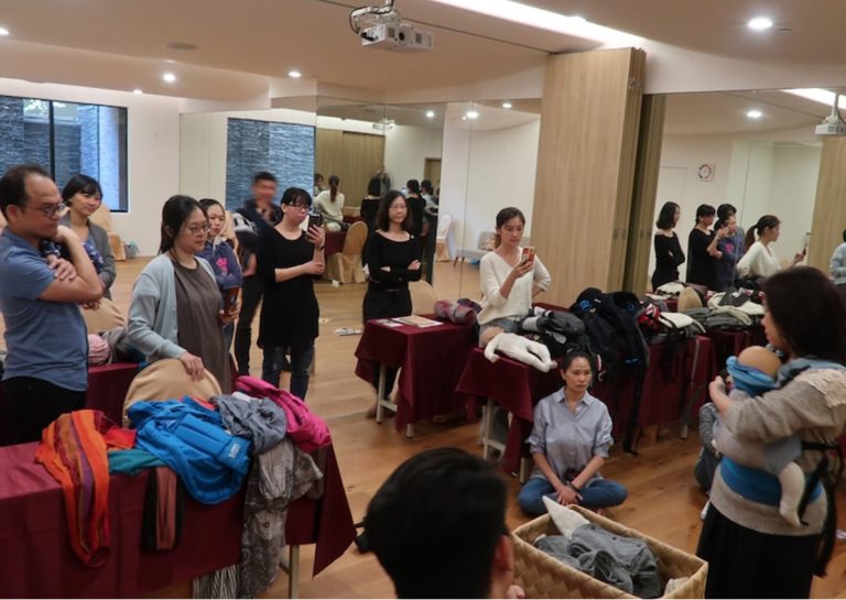 專業揹巾顧問培訓的理論教學現場,學員學習如何評估不同品牌(長布、環揹、SSC)的結構差異,建立客觀的育兒輔具推薦專業能力。