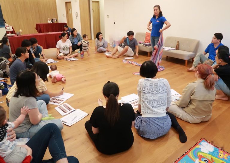 講師在圓圈討論中示範揹巾的操作重點,展示參與式教學如何讓每位學員都能清楚觀察細節,增進團體互動與學習動力。