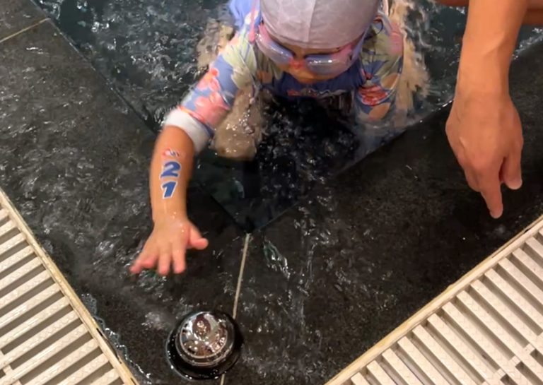 學員在完成挑戰性極高的水中耐力賽後,上岸按響銀色鈴鐺代表順利完賽。這項挑戰旨在考驗兒童的閉氣耐受力與水中持續推進能力,並透過按鈴的儀式感建立強大的成就感與目標達成意識。
